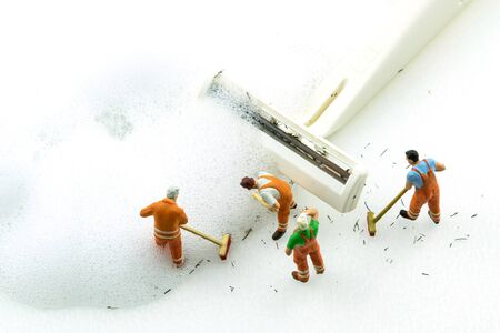 Miniature people cleaning dirty white shaver on white background.の写真素材