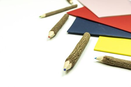 Colored pencils made from branches of trees and colored books isolate on white background.