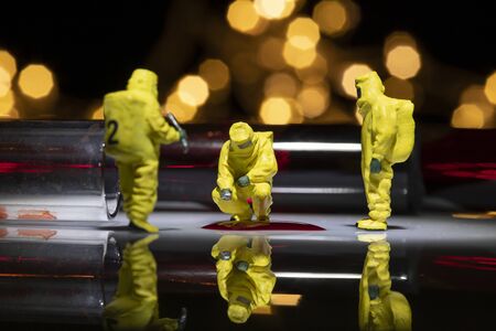 Miniature people wear protective clothing to check blood for test Covid-19.