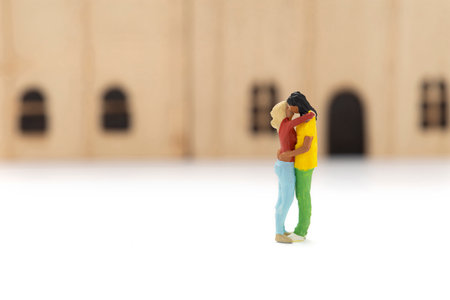 Miniature people standing hugging and kissing each other, the background of the house is blurry.の写真素材