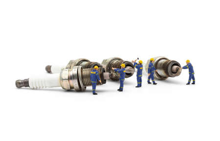 Miniature mechanic with old used engine spark plugs on white background.の写真素材