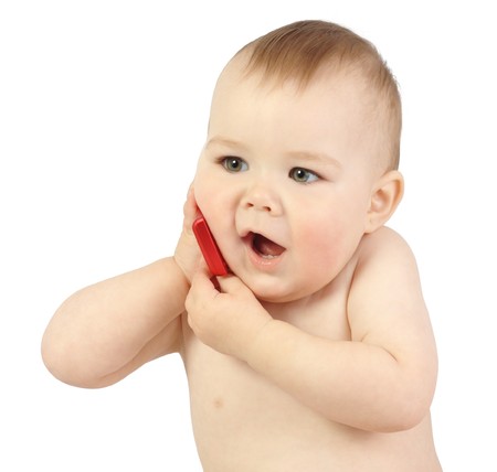 Cute child talking to a cell phone, isolated over whiteの写真素材