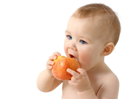 Beautiful child eats red apple, isolated over whiteの写真素材