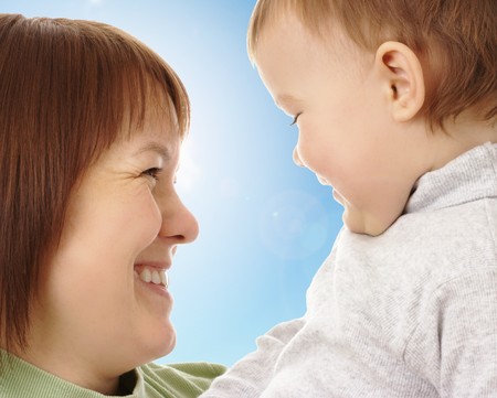 Happy mother looking at her child, blue sky in backgroundの写真素材