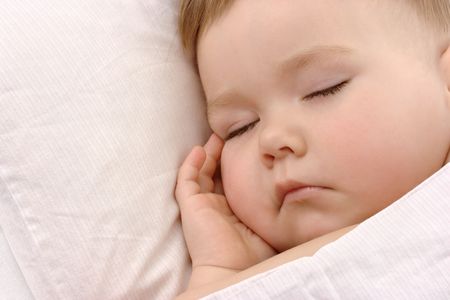 Child sleeping with hand under his cheek, high key porteredの写真素材