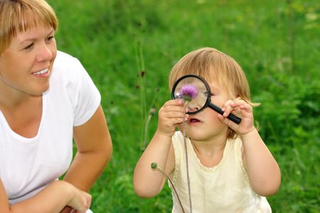 Cute little girl looking at flowers through magnifying glassの写真素材