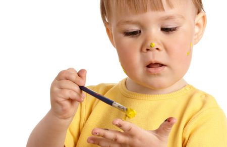 Cute little girl paint on her palm with yellow paint, isolated over whiteの写真素材