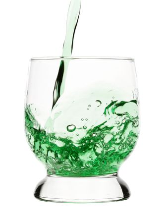 Green drink is being poured into glass, isolated over whiteの写真素材
