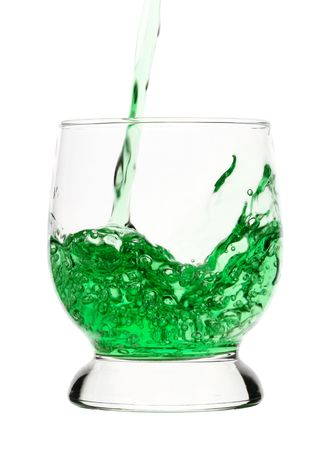 Green drink is being poured into glass, isolated over whiteの写真素材