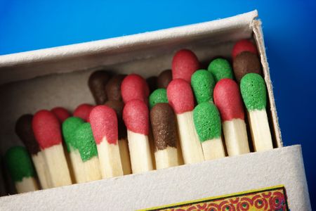 Multicolored matchsticks in the box on blue background, shallow DOF