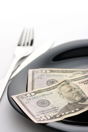 One hundred dollars on black plate with fork and knifeの写真素材