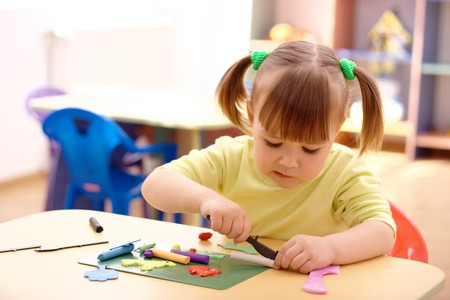 Cute little girl play with plasticine in preschoolの写真素材