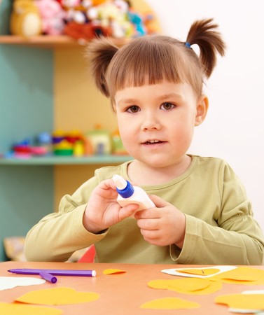 Cute little girl doing arts and crafts in preschoolの写真素材