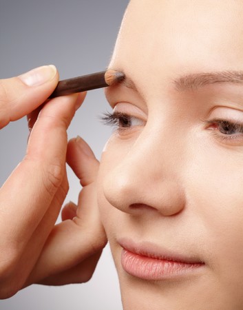 Stylist is penciling eyebrow for young girlの写真素材