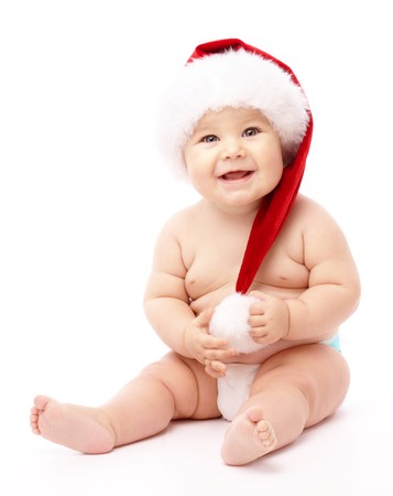 Adorable child is sitting on floor, wearing red Christmas cap, isolated over whiteの写真素材