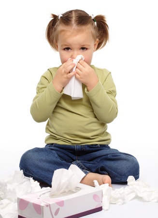 Little girl blows her nose while sitting on floor, isolated over white Little girl blows her nose while sitting on floor, isolated over white