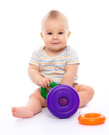 Cute little boy is playing with toys while sitting on floor, isolated over whiteの写真素材
