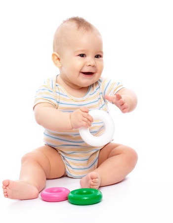 Cute little boy is playing with toys while sitting on floor, isolated over whiteの写真素材