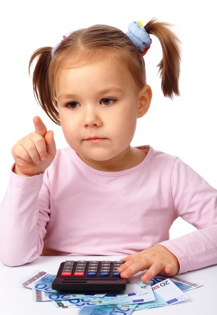 Cute little girl plays with money pointing at something by her finger, isolated over whiteの写真素材