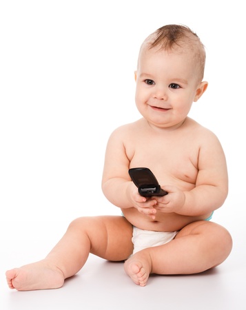 Happy little baby plays with mobile phone, isolated over whiteの写真素材