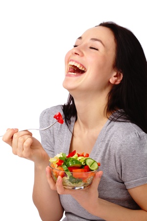 Young attractive woman eats vegetable salad using fork, isolated over whiteの写真素材