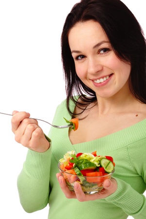 Young attractive woman eats vegetable salad using fork, isolated over whiteの写真素材
