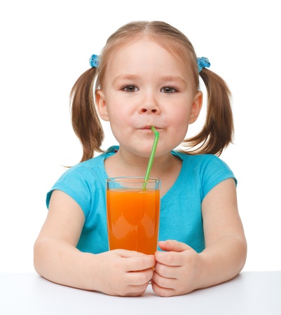 Cute little girl drinks orange juice using drinking straw, isolated over whiteの写真素材
