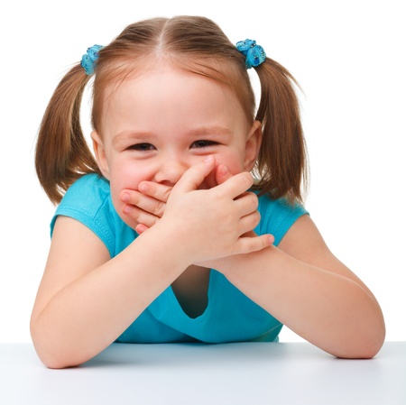 Portrait of a cute little girl covering her mouth with hands, isolated over whiteの写真素材