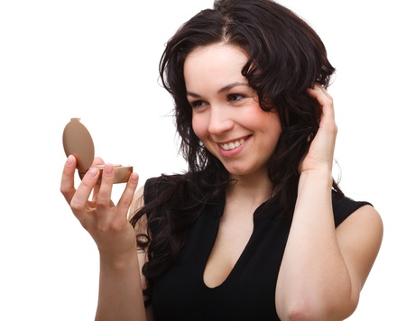 Young attractive girl is looking at herself in small mirror, isolated over whiteの写真素材
