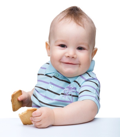 Cute cheerful little boy is holding cookies and smile, isolated over whiteの写真素材