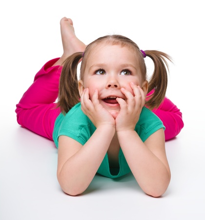 Portrait of a cute little girl laying on floor and smile, isolated over whiteの写真素材