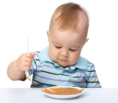 Cute little boy is playing with fruit puree, isolated over whiteの写真素材