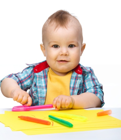 Happy little boy is playing with colorful markers, isolated over whiteの写真素材