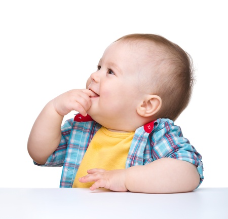 Portrait of a cute little boy biting his finger, isolated over whiteの写真素材