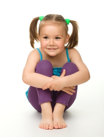 Portrait of a cute little girl sitting on floor, isolated over whiteの写真素材