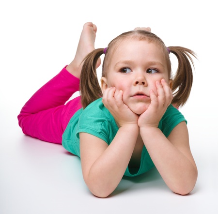 Portrait of a cute little girl laying on floor and smile, isolated over whiteの写真素材