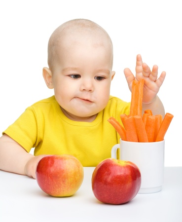 Little boy pulling up carrot from a cup, isolated over whiteの写真素材