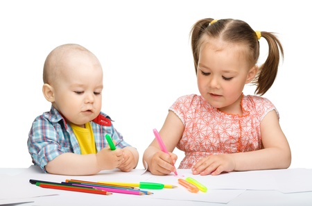 Two children, girl and boy, are drawing on paper using markers, isolated over whiteの写真素材
