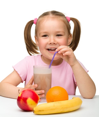 Cute little girl drinks fruit juice using drinking straw, isolated over whiteの写真素材