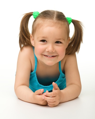 Portrait of a cute happy little girl laying on floor, isolated over whiteの写真素材