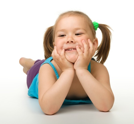 Portrait of a cute little girl laying on floor and holding her head with hands, isolated over whiteの写真素材