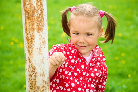 Happy little girl is playing on green meadowの写真素材
