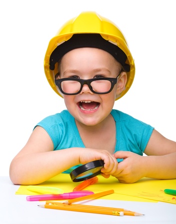 Cute little girl is playing while wearing hard hat, isolated over whiteの写真素材
