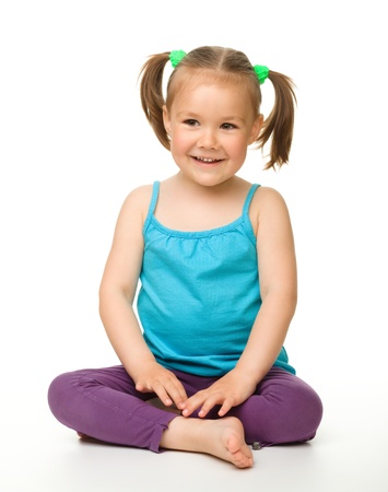 Portrait of a cute little girl sitting on floor, isolated over whiteの写真素材