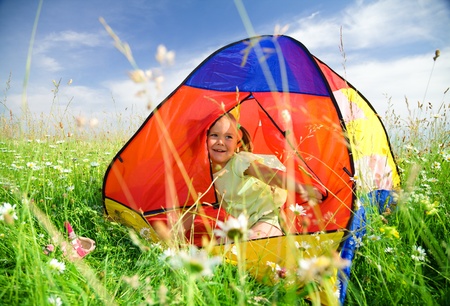 Cute little girl is playing outdoors under tentの写真素材