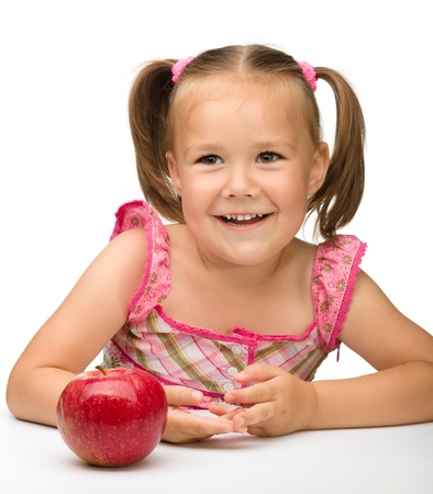 Portrait of a cute cheerful little girl with red apple, isolated over whiteの写真素材