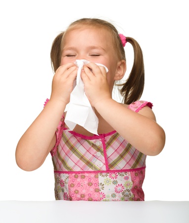 Little girl blows her nose, isolated over whiteの写真素材