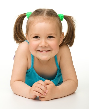Portrait of a cute happy little girl laying on floor, isolated over whiteの写真素材