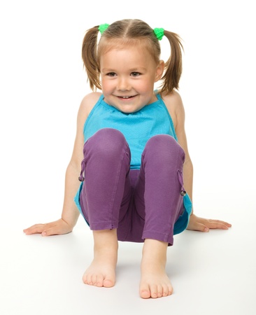 Portrait of a cute happy little girl laying on floor, isolated over whiteの写真素材