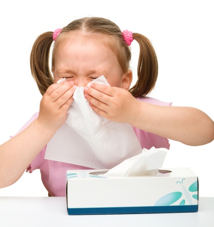 Little girl blows her nose, isolated over whiteの写真素材
